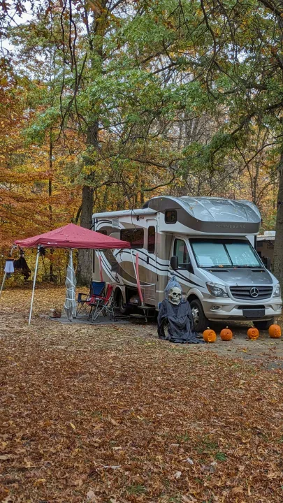 An RV rental is decorated for Halloween at an autumn campsite, surrounded by fall leaves, a skeleton, and carved pumpkins.. Winnebago View 24G 2016