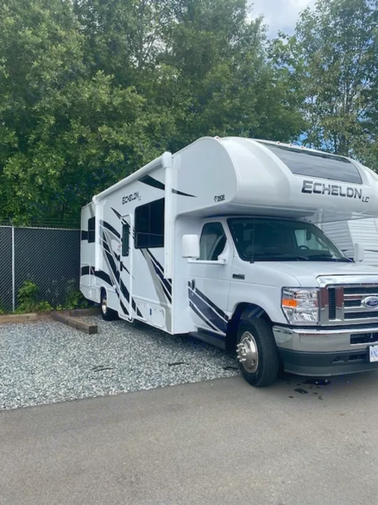 White Echelon LC RV rental with graphics, parked on gravel. Class C motorhome ready for travel.. Thor Echelon 2022