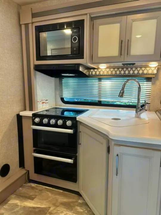 RV rental kitchen: compact, yet complete with microwave, stove, sink, and ample counter space for your travels.. Thor Echelon 2022