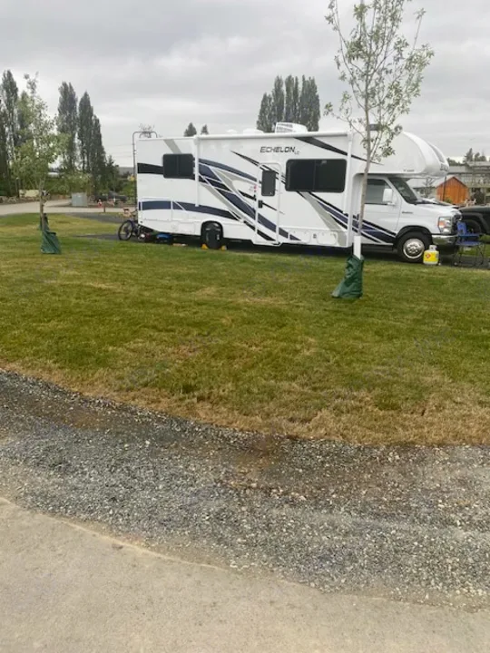 White Echelon RV rental with blue/gray graphics parked on a grassy site. Ideal for camping and outdoor trips.. Thor Echelon 2022