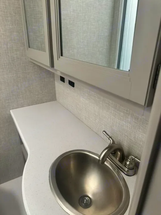 RV rental: Compact bathroom vanity with stainless sink, brushed faucet, mirrored cabinet, and convenient USB outlets.. Thor Echelon 2022