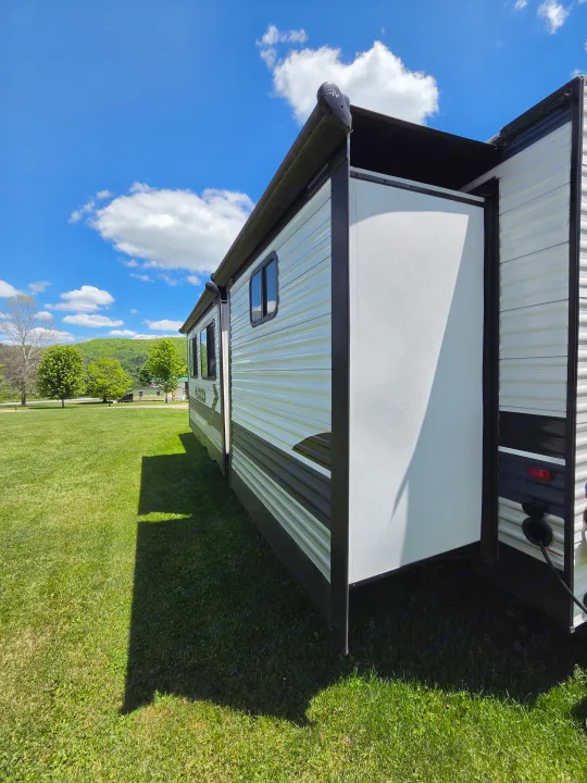 Experience freedom with an rv rental! This travel trailer with its extended slide-out is perfectly set up in a sunny, green campground.. Crossroads RV Zinger 2021