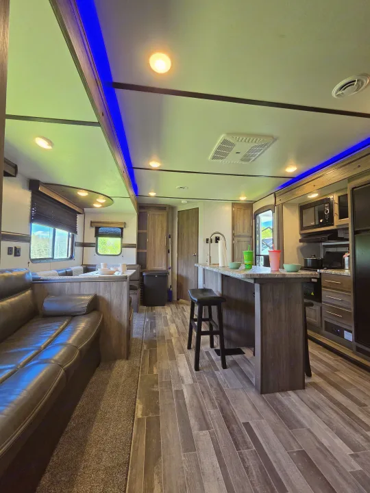 Spacious rv rental interior with living area, kitchen island, dinette, and blue accent lighting.. Crossroads RV Zinger 2021