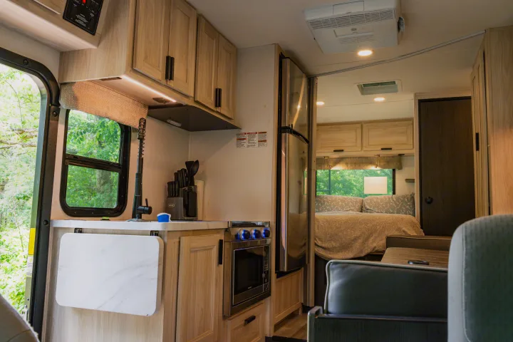 Explore this modern rv rental's interior: functional kitchen, dining area, and cozy bedroom, surrounded by nature views.. Forest River Sunseeker LE 2024
