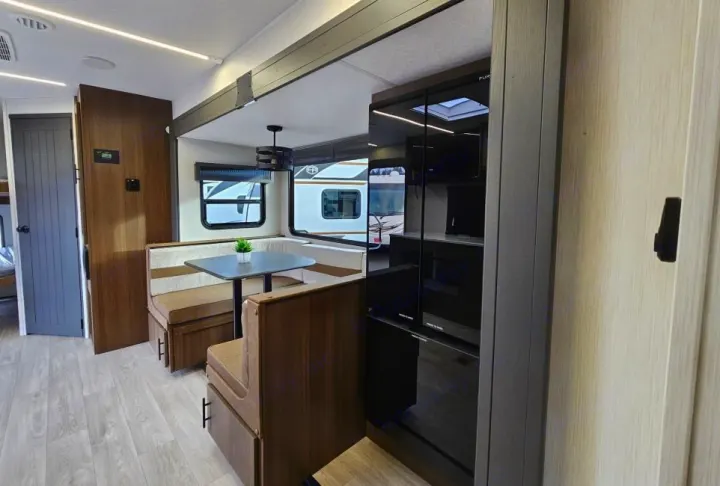 Spacious RV rental interior featuring a cozy dinette, modern kitchen area, and sleek wood finishes for comfortable travel.. Forest River 246DBX 2026