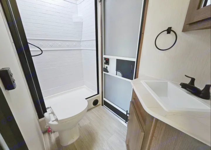 This RV rental bathroom features a white shower, toilet, and sink with a modern vanity, ideal for compact travel.. Forest River 246DBX 2026