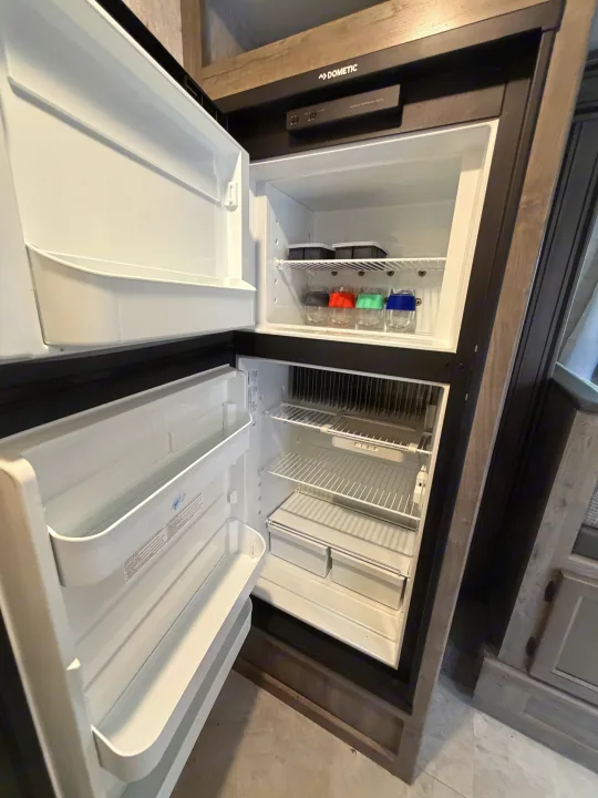 Open Dometic RV refrigerator with top freezer (ice trays/glasses) and bottom fridge with shelves, great for your rv rental.. Coachmen Apex Nano 2022