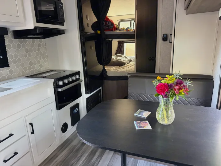 Modern rv rental interior showcasing kitchen, dining area with fresh flowers, and cozy bunk beds.. Jayco Jay Flight Baja Edition 2024