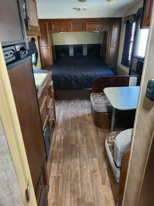 RV rental interior: A cozy bedroom with a large bed, a compact kitchen counter with a sink, and a comfortable dinette booth.. Sonic Sonic Trailer 2019
