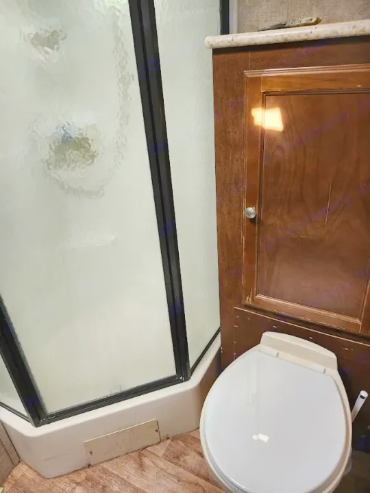 Compact RV rental bathroom: corner shower with frosted glass, toilet, and wood cabinet. Functional, small space.. Sonic Sonic Trailer 2019