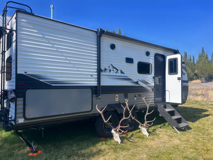 Modern RV rental on grass with door open, featuring two elk skulls & antlers. Perfect for outdoor adventures like hunting.. Jayco Jay Flight Baja Edition 2024
