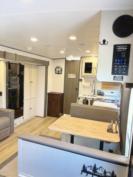 Cozy modern RV rental interior featuring a bright dinette area, compact kitchen, and refrigerator. Ready for adventures!. Forest River Coachmen Northern Spirit Ultra Lite 2026