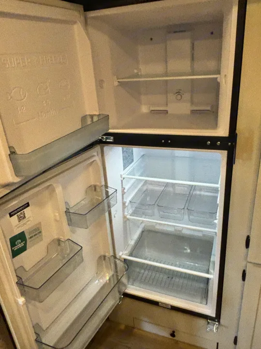 Empty, pristine two-door refrigerator and freezer within an rv rental, featuring shelves & door bins for storage.. Forest River Coachmen Northern Spirit Ultra Lite 2026