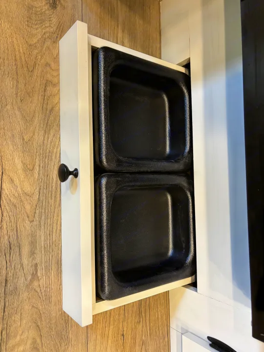 Open drawer in an RV rental, revealing two black, textured storage bins. Practical organization for compact living spaces.. Forest River Coachmen Northern Spirit Ultra Lite 2026