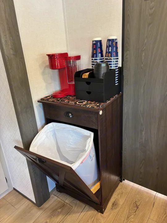 RV rental coffee station with red coffee maker, cups, organizer, and convenient tilt-out trash can in a dark wood cabinet.. Forest River Coachmen Northern Spirit Ultra Lite 2026