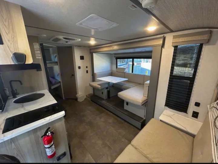 Spacious RV rental interior featuring a modern kitchen, dinette with U-shaped seating, and bunk beds in the back.. Forest River Salem FSX 2025