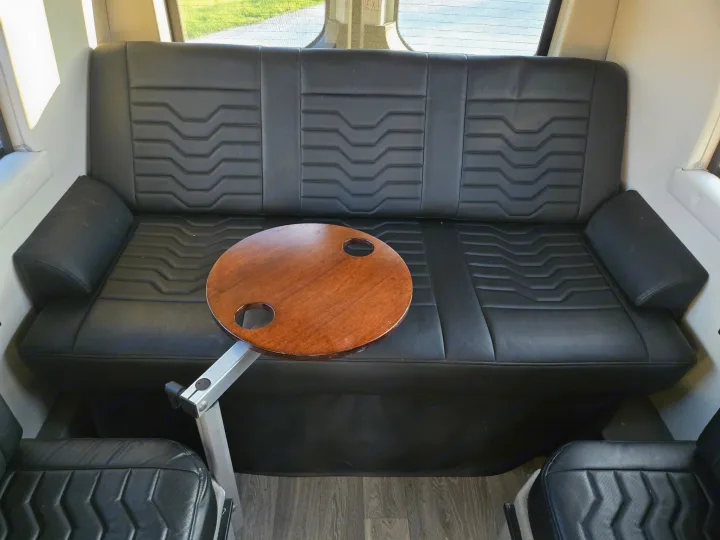 Spacious RV rental interior with black faux leather seating & movable wooden table, perfect for a camper van.. Coachmen Galleria 2023