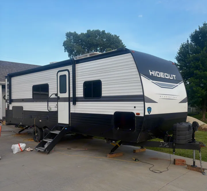 A black and white Keystone Hideout RV rental, a travel trailer, is parked on pavement.. Keystone RV Hideout 2024