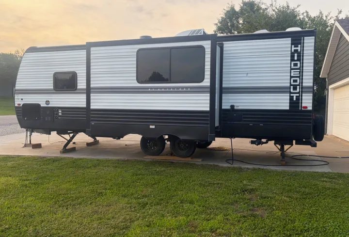 A Keystone Hideout RV rental, parked on concrete with its slide-out extended and stabilizer jacks down.. Keystone RV Hideout 2024