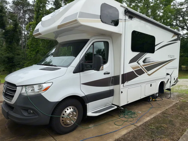 White Class C rv rental, a Mercedes-Benz Jayco Melbourne motorhome, hooked up at a leafy green campsite.. Jayco Melbourne 2024