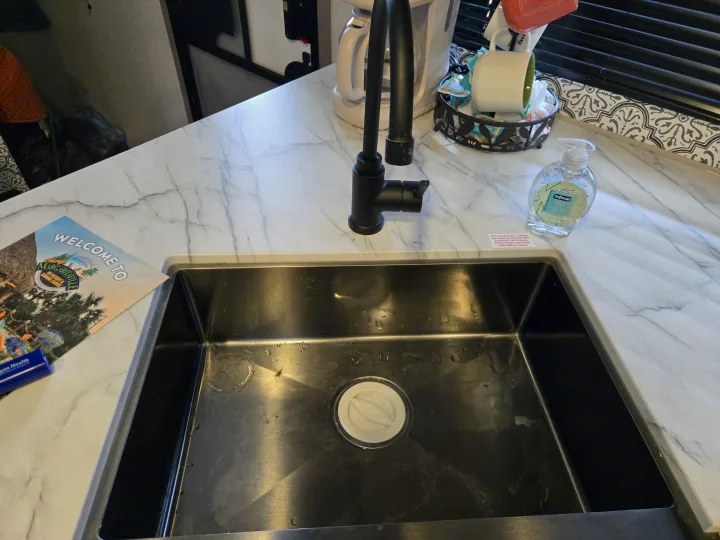 RV rental kitchen with sink, faucet, coffee maker, and welcome guide. Note about flushing non-toxic anti-freeze.. Dutchmen Coleman Lantern 2022