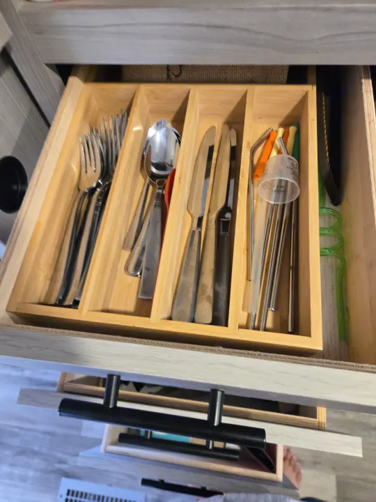 RV rental kitchen drawer: a wooden organizer neatly holds silverware (forks, spoons, knives), metal, and green reusable straws.. Dutchmen Coleman Lantern 2022