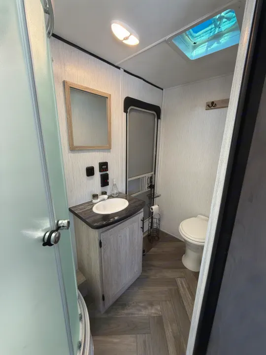 Well-appointed RV rental bathroom showcasing a modern vanity, sink, mirror, toilet, shower, and ceiling fan.. Heartland RVs Prowler 2022