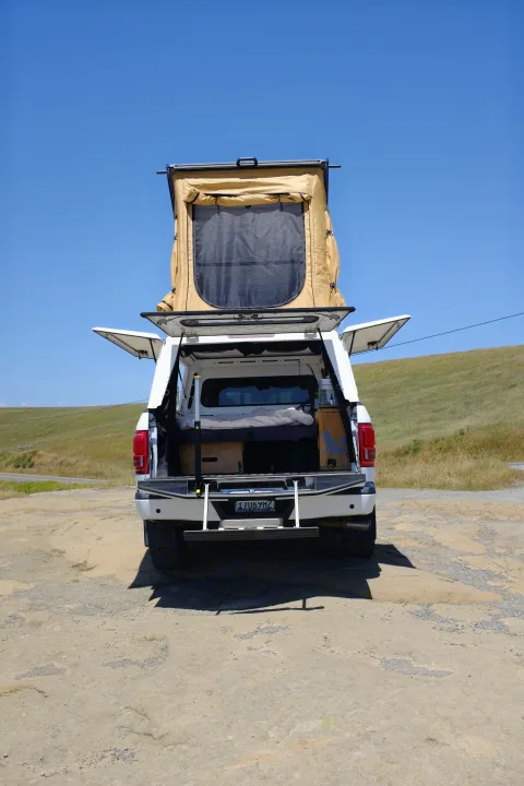 rv rental: White pickup truck with deployed rooftop tent, open camper shell revealing a sleeping setup. Ready for outdoor adventure!. Ford Ford F150 2017