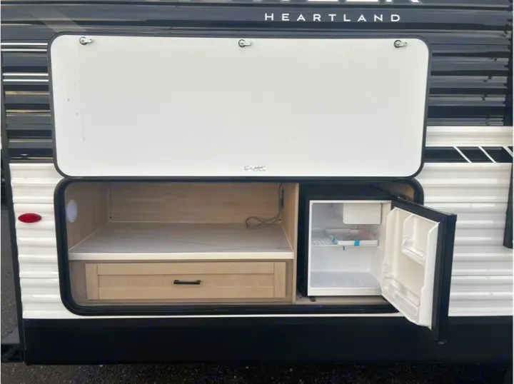 RV rental's exterior features an open outdoor kitchen with a mini-fridge, drawer, and counter for convenient camping.. Heartland Powler 2026