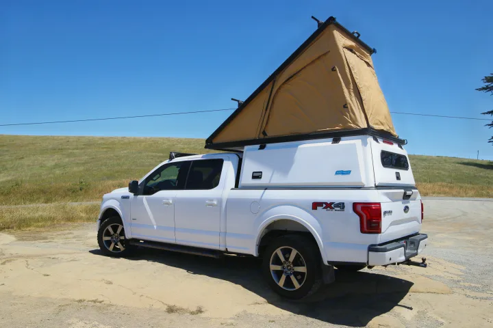 White Ford F-150 overland truck with a pop-top rooftop tent and camper shell, ready for your RV rental camping adventure.. Ford Ford F150 2017