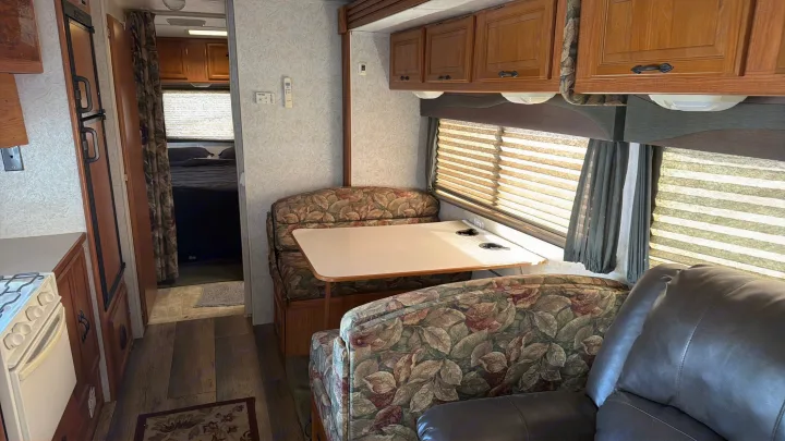 Cozy rv rental interior: dinette, kitchen, and bedroom. Experience comfort on your road trip!. Coachmen Leprechaun 2003