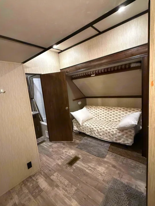 RV rental interior featuring a bunk bed with white pillows, adjacent to an open bathroom with a shower.. Crossroads RV Volante 2020