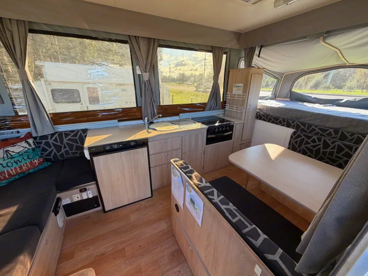 This rv rental pop-up camper's interior features a compact kitchen, dining area, and bed, offering a cozy mobile home setup.. Outback Eagle Off-Road 2015