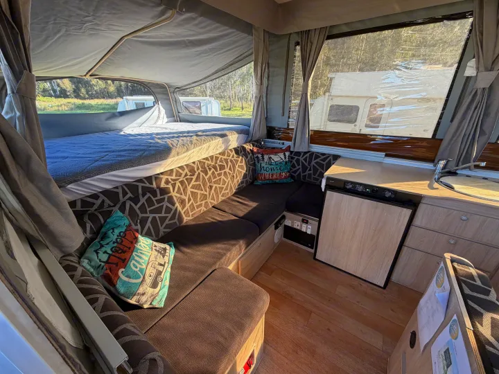 Inside a comfortable rv rental: a cozy pop-up camper interior with bed, sofa, kitchen, and scenic outdoor views.. Outback Eagle Off-Road 2015