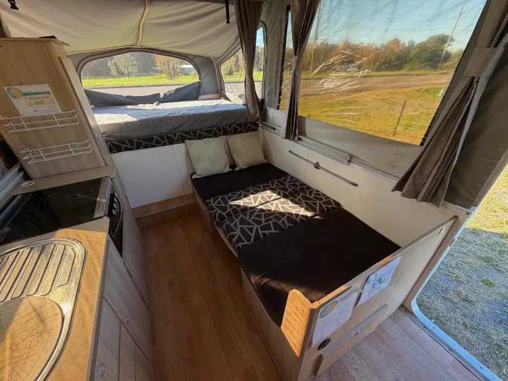 Inside a bright rv rental: pop-up camper with beds, dinette, kitchen, and scenic outdoor views through clear windows.. Outback Eagle Off-Road 2015