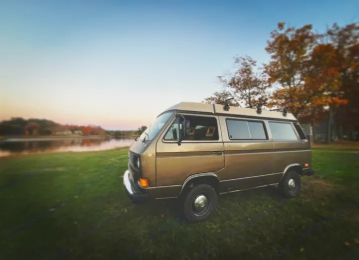 Retro camper van RV rental parked lakeside at sunset, ideal for nature adventures.. Volkswagen Westfalia 1985