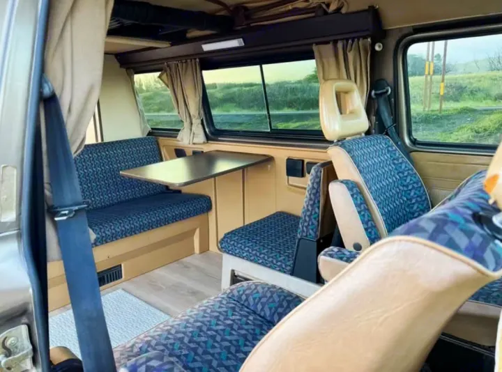 Step inside this inviting rv rental! Features patterned seating, a dining table, and windows with scenic views.. Volkswagen Westfalia 1985