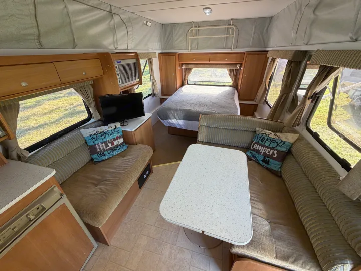 Comfortable rv rental interior with a bed, lounge, dining table, and kitchenette, perfect for your next adventure.. Jayco J Series 2008