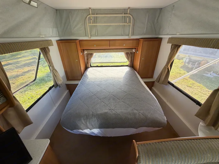 Cozy RV rental bedroom with a comfy bed, wood cabinetry, and scenic windows for your next road trip adventure.. Jayco J Series 2008