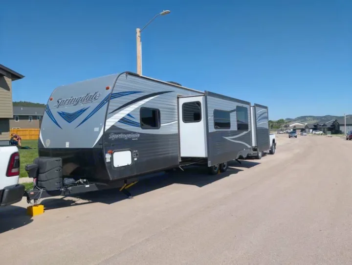 Spacious Springdale RV rental, with slide-outs extended, parked on a sunny residential street for your next adventure.. Keystone RV Springdale 2019