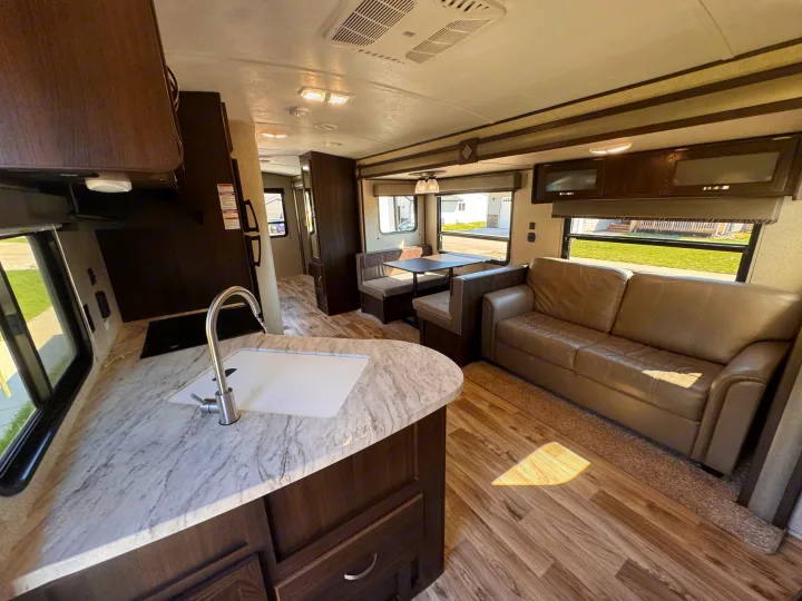 Spacious rv rental interior featuring a kitchen counter, comfortable sofa, and dinette, perfect for travel comfort.. Keystone RV Springdale 2019