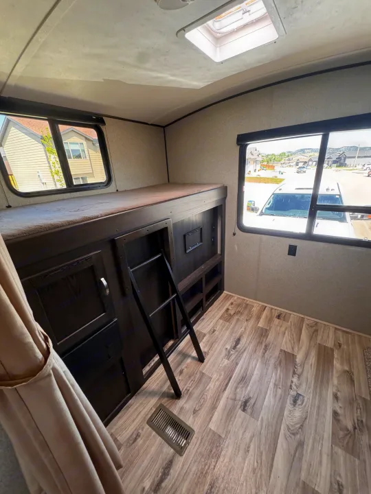 Interior of an RV rental: Bunk bed with ladder, skylight, and windows for your family's trip.. Keystone RV Springdale 2019