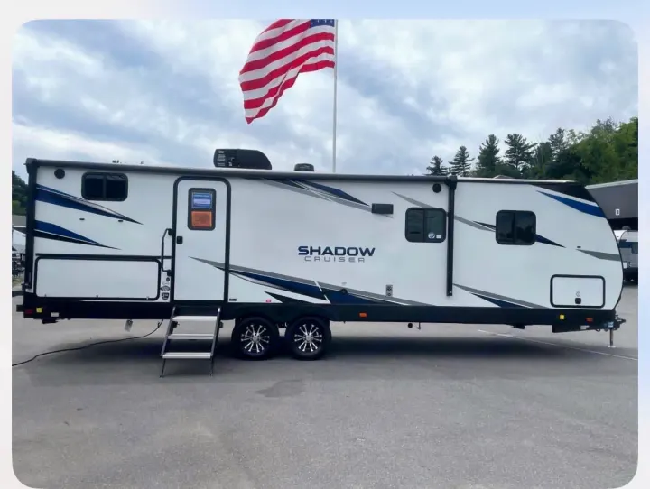 Spacious white Shadow Cruiser travel trailer, perfect for your next RV rental adventure. Note the blue graphics & American flag.. Shadow Trailers 277bhs 2022