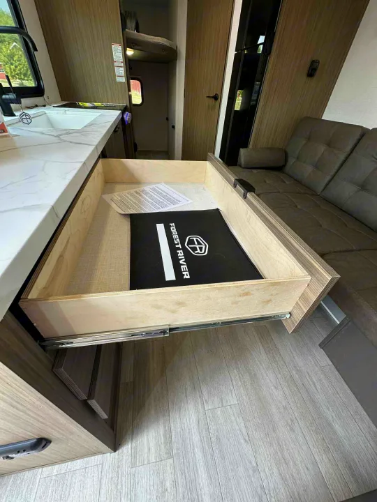 RV rental's kitchen area with an open drawer containing owner's guides, a sink, and a comfortable sofa.. Forest River Salem FSX 266BHLE 2026
