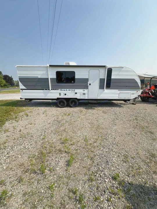 Explore the outdoors! This white Salem FSX travel trailer is available for RV rental, parked on a gravel lot.. Forest River Salem FSX 266BHLE 2026