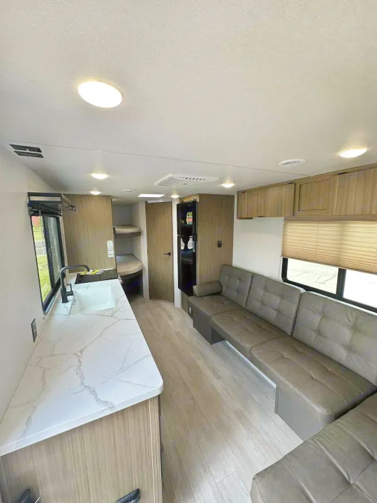 Spacious rv rental interior: Modern kitchen, cozy bunk beds, and a large sectional sofa. Ideal for travel comfort and family fun.. Forest River Salem FSX 266BHLE 2026