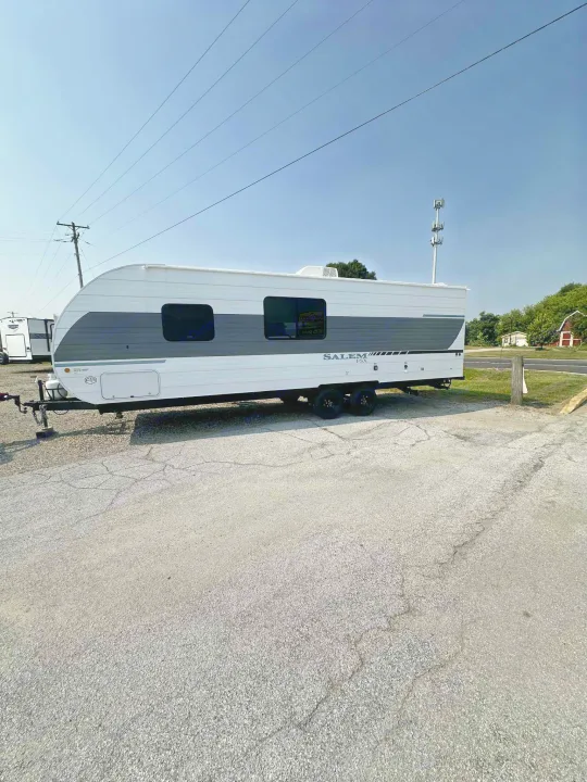 White and grey Salem FSX travel trailer for rv rental, parked on an asphalt lot under a clear blue sky.. Forest River Salem FSX 266BHLE 2026