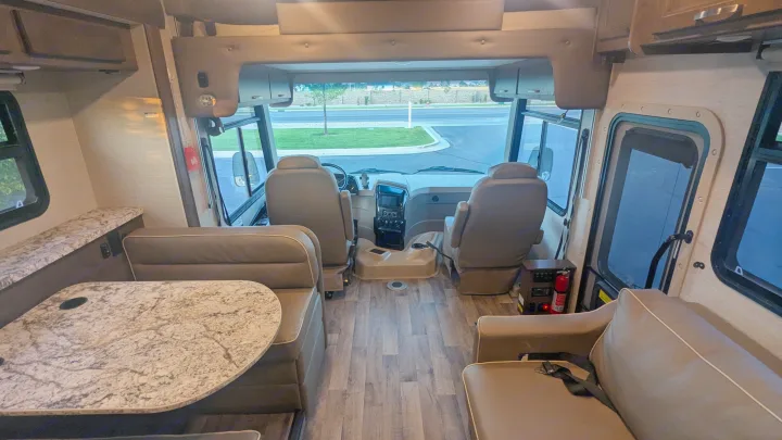 Spacious rv rental interior with front cockpit, driver/passenger seats, dinette, and sofa. Features modern design & wood-look floor.. Jayco Alante 2020