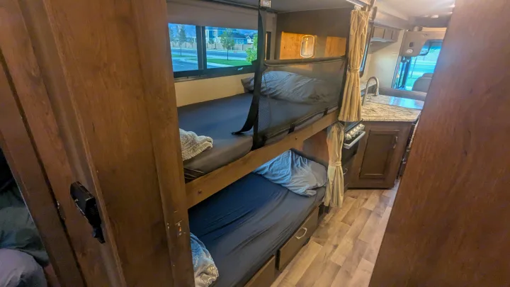 RV rental interior features bunk beds with safety net, visible kitchen, and outdoor view from window.. Jayco Alante 2020
