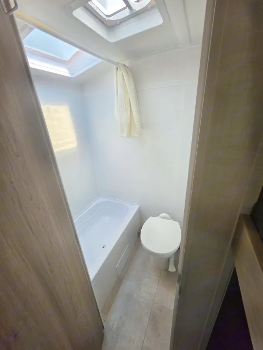 RV rental bathroom featuring a white shower/tub, toilet, and a bright skylight. A white towel hangs above the tub.. Forest River Rockwood Geo Pro 2026